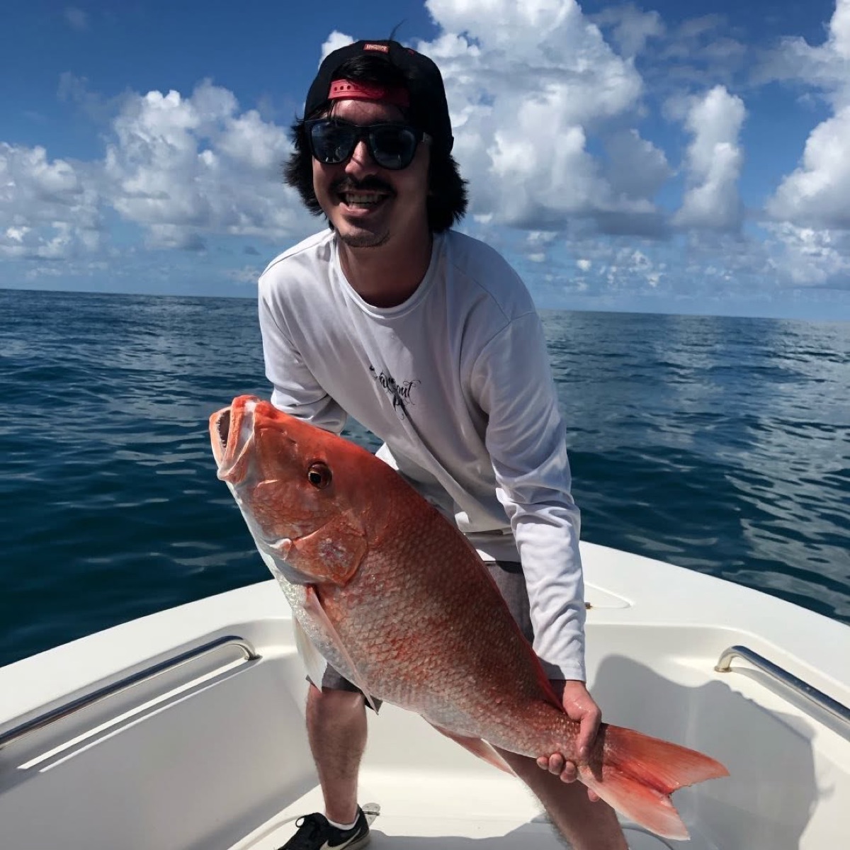 Zach on a boat holding a large red snapper