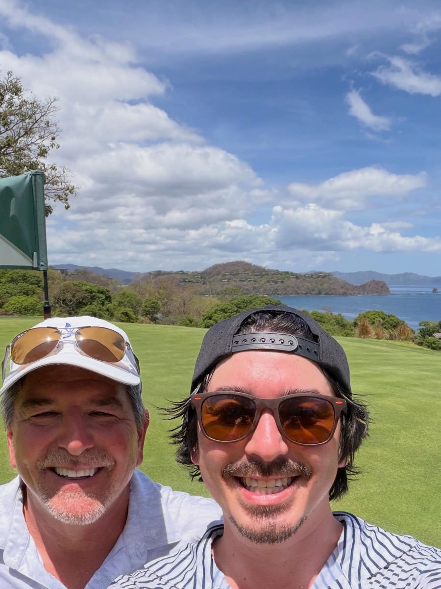 Zach and his dad on a golf course overlooking the ocean
